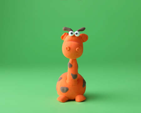 Small giraffe made from play dough on green backgroundの写真素材