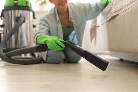 Young woman vacuuming floor in bedroom, closeupの写真素材