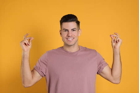 Handsome man snapping fingers on yellow background
