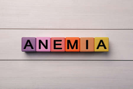 Word Anemia made with colorful cubes on white wooden table, flat layの写真素材