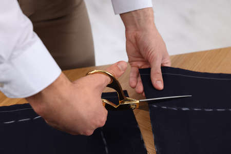 Dressmaker cutting fabric by following chalked sewing pattern in workshop, closeupの写真素材