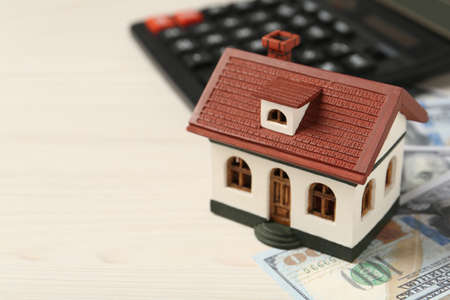 Mortgage concept. House model, calculator and money on white wooden table, closeup with space for textの写真素材