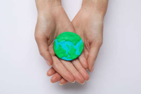 Woman holding plastic model of planet on white background, top view. earth dayの写真素材