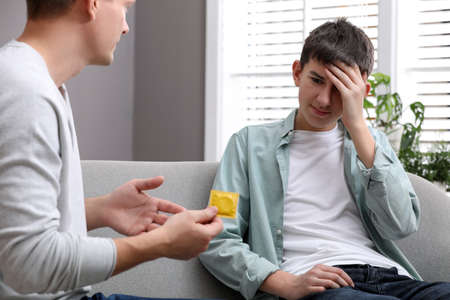 Father talking with his teenage son about contraception at home. sex education conceptの写真素材