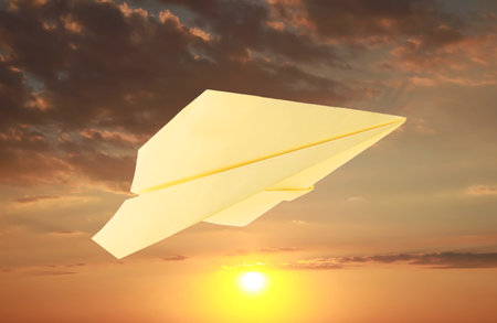 Yellow paper plane and view of beautiful sky at sunsetの写真素材