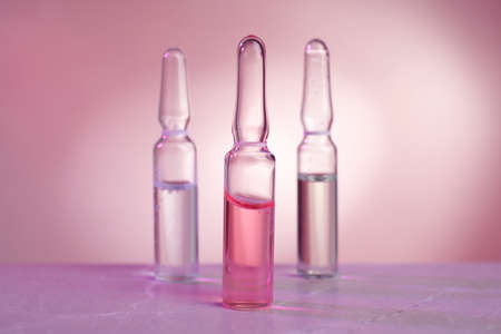 Pharmaceutical ampoules with medication on gray table against color background.の写真素材