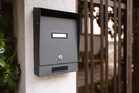 Black metal mailbox outdoors near entrance on spring day