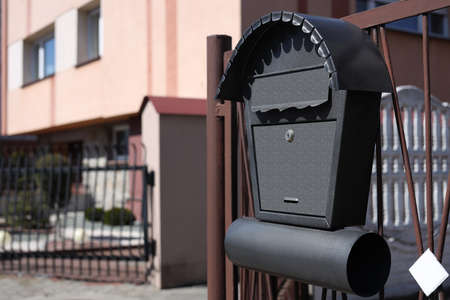 Beautiful mailbox with newspaper holder on metal fence outdoors, space for textの写真素材