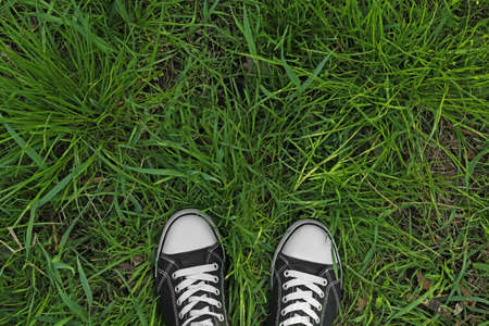 Person in gumshoes standing on green grass outdoors, top view