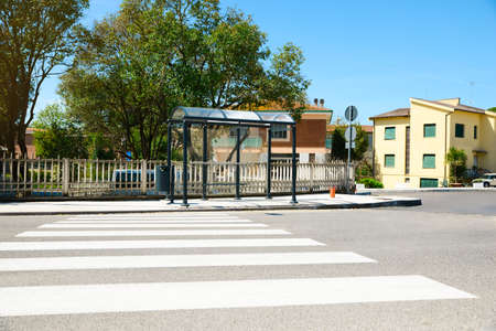 Public transport stop with bench and glass roof on city streetの写真素材