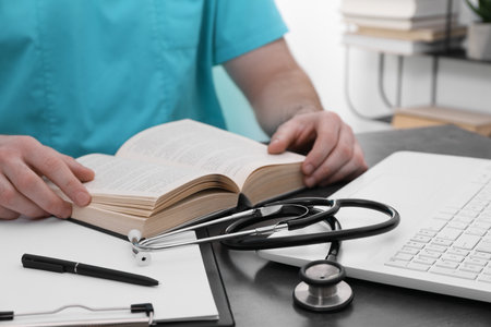 Medical student in uniform studying at table indoors, closeupの写真素材