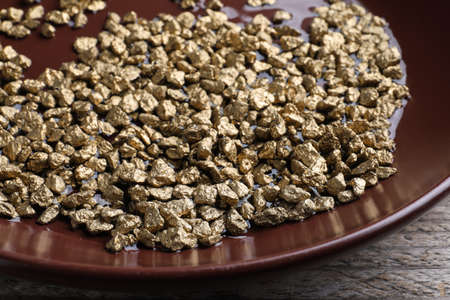 Plate of gold nuggets on wooden table, closeupの写真素材