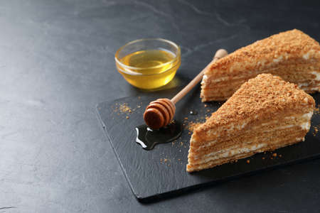 Slices of delicious layered honey cake served on a black table. Space for textの写真素材