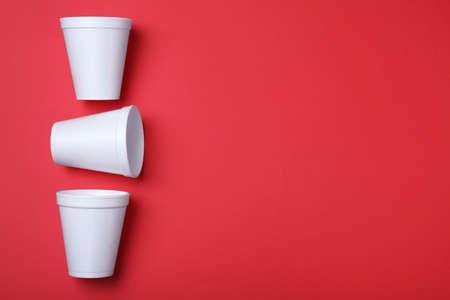 White cups on red background, flat lay. Space for textの写真素材