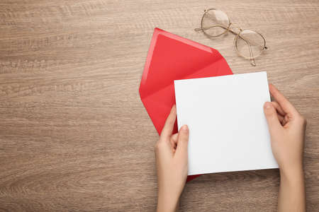Woman with blank letter on wooden table, top view. Space for text