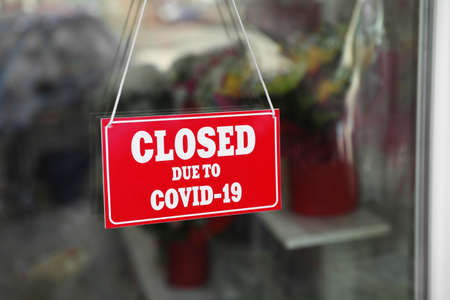 Red sign with text Closed Due To Covid-19 hanging on glass door. Coronavirus quarantineの写真素材