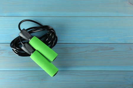 Skipping rope on light blue wooden table, top view. Space for textの写真素材