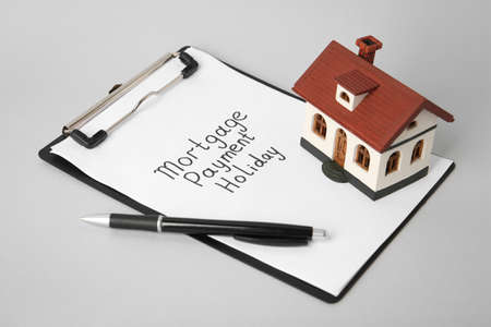 House model, clipboard with text Mortgage payment holiday and pen on light gray tableの写真素材