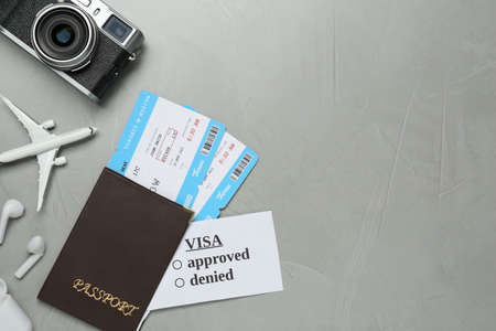 Flat lay composition with passport, toy plane and camera on gray background, space for text.