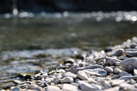 River coast with stones and pebbles on sunny dayの写真素材