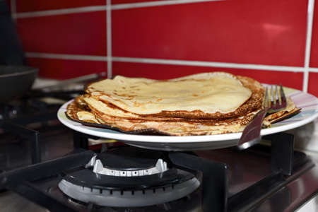 Plate of freshly made crepes with fork on stove in kitchen, closeupの写真素材