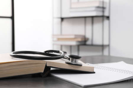 Open student textbook and stethoscope on gray table indoors. medical educationの写真素材