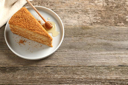Slice of delicious layered honey cake served on wooden table, above view. Space for textの写真素材