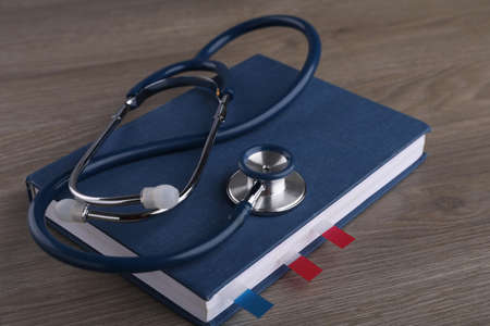 Book with sticker marks and stethoscope on wooden table. medical educationの写真素材