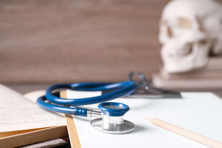 Open student textbook, clipboard and stethoscope on table, closeup. medical education