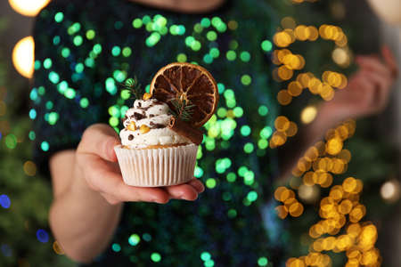 Woman with Christmas cupcake against blurred festive lights, closeupの写真素材