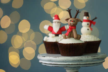 Tasty Christmas cupcakes on dessert stand against blurred festive lights, space for textの写真素材