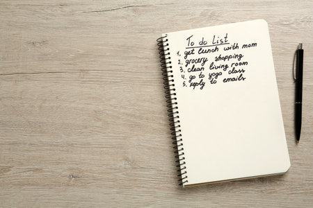 Notebook with to do list and pen on white wooden table, flat lay. Space for textの写真素材
