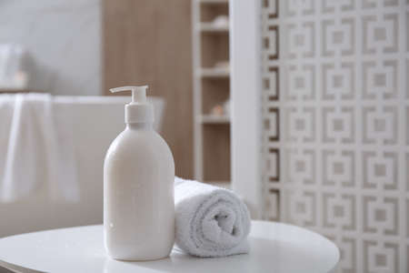 Bottle of shower gel and fresh towel on white table in bathroom. Space for textの写真素材