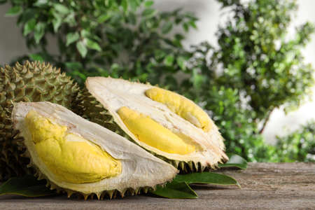 Fresh ripe durian fruits on wooden table, space for text