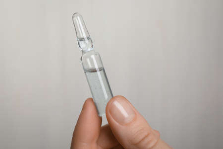 Woman holding pharmaceutical ampoule with medication on white background, closeupの写真素材