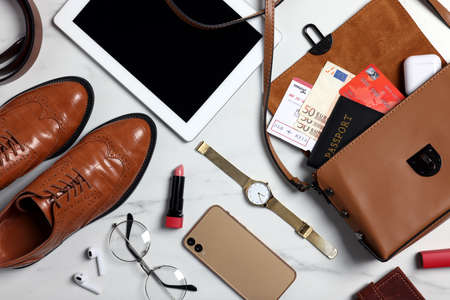 Flat lay composition with documents, money and accessories on white marble background. Packing for...
