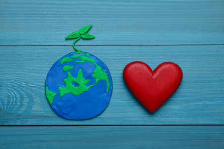 Happy Earth Day. Plasticine planet and decorative heart on turquoise wooden table, flat layの写真素材