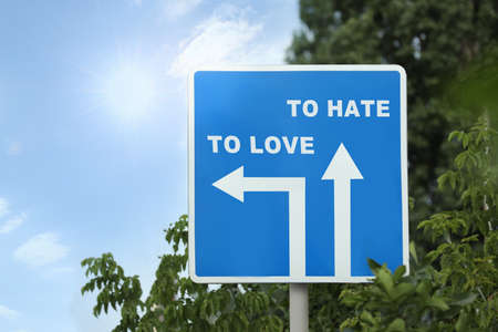 Road sign with different directions - TO HATE or TO LOVE outdoorsの写真素材