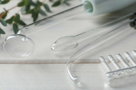 Darsonval with different nozzles on white wooden table, closeup