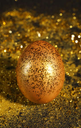 Shiny golden egg with glitter on dark tableの写真素材