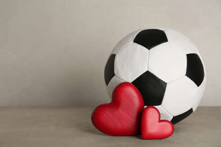 Soccer ball and hearts on gray table against light background. Space for textの写真素材
