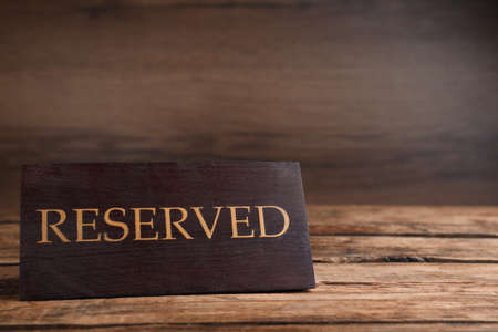 Elegant sign RESERVED on wooden surface, space for text. Table setting elementの写真素材