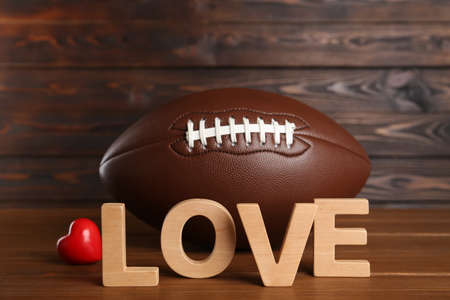 American football ball, heart and word Love on wooden tableの写真素材