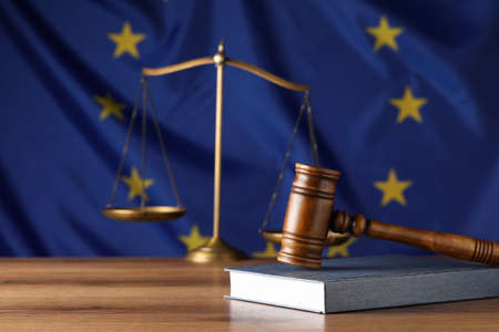 Judge's gavel and book on wooden table against European Union flag. Space for textの写真素材