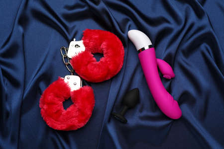 Sex toys and handcuffs on blue silky fabric, flat layの写真素材