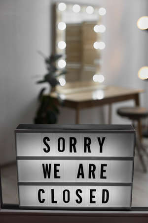 Lightbox with text SORRY WE ARE CLOSED hanging on glass door.の写真素材