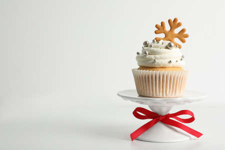 Tasty Christmas cupcake with cream and snowflake cookie on white background, space for textの写真素材