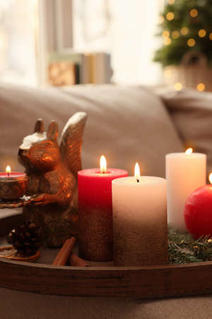 Tray with beautiful burning candles and Christmas decor on sofa at home, closeupの写真素材