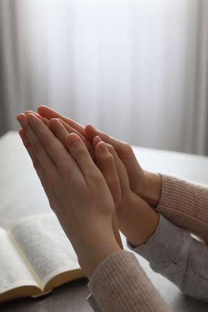 Boy and his godparent praying together at gray table indoors, closeupの写真素材