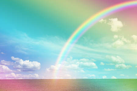 Picturesque view of green meadow and beautiful rainbow in blue sky on sunny dayの写真素材